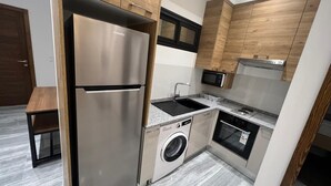 Une cuisine compacte équipée d’un réfrigérateur en acier inoxydable, d’un lave-linge encastré, d’un four à micro-ondes et d’une cuisinière.