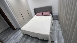 Une chambre à coucher avec un lit, une table de chevet, une armoire et un rideau.