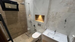 Une salle de bain moderne avec une douche à parois de verre, des toilettes et un lavabo.