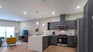 A modern kitchen with grey cabinets, a central island, a microwave, and a refrigerator. - 324 Brand New 1 Bedroom, 1 Bath, 1 Kitchen, 1 Liv (Dunellen)