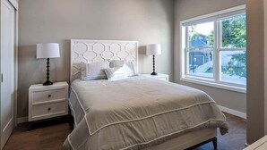 A bedroom with a bed, two bedside tables, a window, and a view of the outside. - 324 Brand New 1 Bedroom, 1 Bath, 1 Kitchen, 1 Liv (Dunellen)