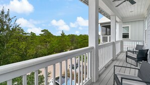 Eine überdachte Veranda mit weißen Geländern, einem Deckenventilator und Gartenmöbeln.