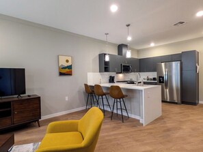 A modern kitchen with a central island, stainless steel appliances, and a bar area with stools. - 210 Brand New 1 Bedroom, 1 Bath, 1 Full Kit, 1 Liv (Dunellen)