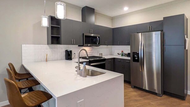 A modern kitchen with a central island, stainless steel appliances, and a white countertop. - 210 Brand New 1 Bedroom, 1 Bath, 1 Full Kit, 1 Liv (Dunellen)