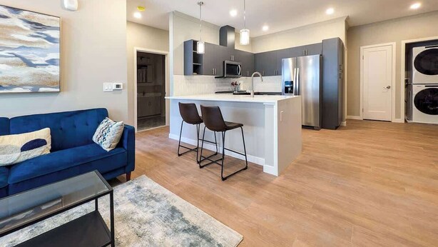 Un apartamento moderno con sala de estar, cocina y una isla grande con taburetes de bar.