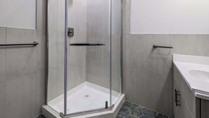 Un baño moderno con ducha de vidrio, lavamanos blanco y paredes con azulejos.
