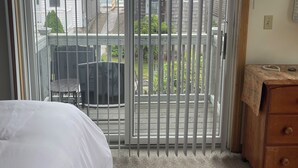 Une chambre d’hôtel dotée d’une grande porte-fenêtre coulissante donnant sur un balcon avec vue sur les maisons voisines et un plan d’eau.