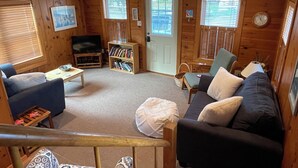 Un salon confortable avec un canapé, des fauteuils, une table basse, une bibliothèque et un téléviseur.