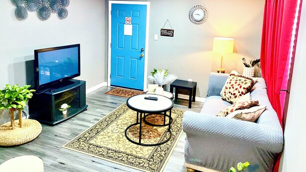 Una sala de estar con televisor, sofá y una puerta azul.