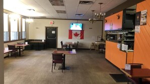 A restaurant interior with booths, tables, a bar area, and a Canadian flag. - Houston Motor Inn (Houston)