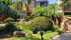 A well-maintained garden with a pond, palm trees, and a wooden bridge. - BreathTaking View of Ocean Blue and Orange Sunsets (Solana Beach)