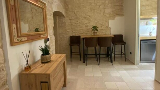 Een eetruimte met een stenen muur, een houten tafel en vier stoelen.