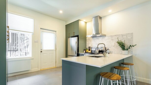 A modern kitchen with a central island, bar stools, a stainless steel refrigerator, and a large window. - HOMA-Comfort&Style-2BR-Spacious-Natural Light-FeelHome-A/C-SelfCheckIn-Metro (Montréal)