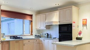A kitchen with light-colored cabinets, a microwave, a toaster, and a sink. - Cozy Highland Retreat With Stunning Views (Invergarry)