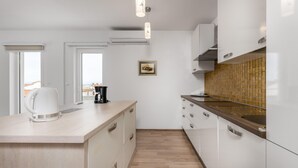 Una cocina moderna con armarios blancos, encimera de madera, cafetera y vistas al exterior a través de una ventana.