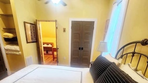 A bedroom with a large bed, a ceiling fan, a wardrobe, and a door leading to another room. - Cozy Loblolly Loft in charming Summerville (Summerville)