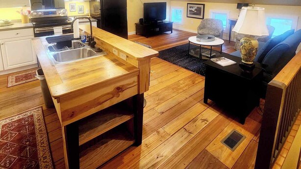 A spacious living area with a wooden dining table, a sofa, a TV, and a ceiling fan. - Cozy Loblolly Loft in charming Summerville (Summerville)