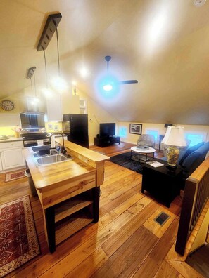 A spacious living area with a wooden dining table, a sofa, a TV, and a ceiling fan. - Cozy Loblolly Loft in charming Summerville (Summerville)