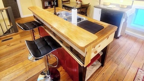 A modern kitchen with a wooden island, bar stools, and a dining table. - Cozy Loblolly Loft in charming Summerville (Summerville)