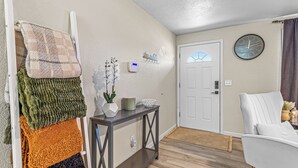 A modern living room with a white sofa, a dark wooden console table, and a wall-mounted clock. - Beautiful & Comfortable Home in Central Point (Central Point)