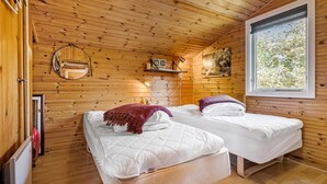 Habitación de cabaña de madera con dos camas, una ventana y un espejo en la pared.