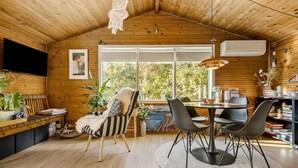 Interior acogedor de una cabaña de madera con comedor, sofá y estantería.