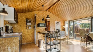 Una cocina moderna con paredes de madera, un ventanal grande y una zona de comedor con un sofá y un perro.