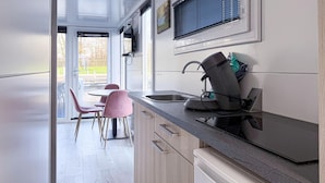 Una cocina moderna con lavavajillas incorporado, un lavabo y un comedor con sillas rosas.