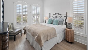 A bedroom with a bed, a chair, a bedside table, a lamp, and a ceiling fan.