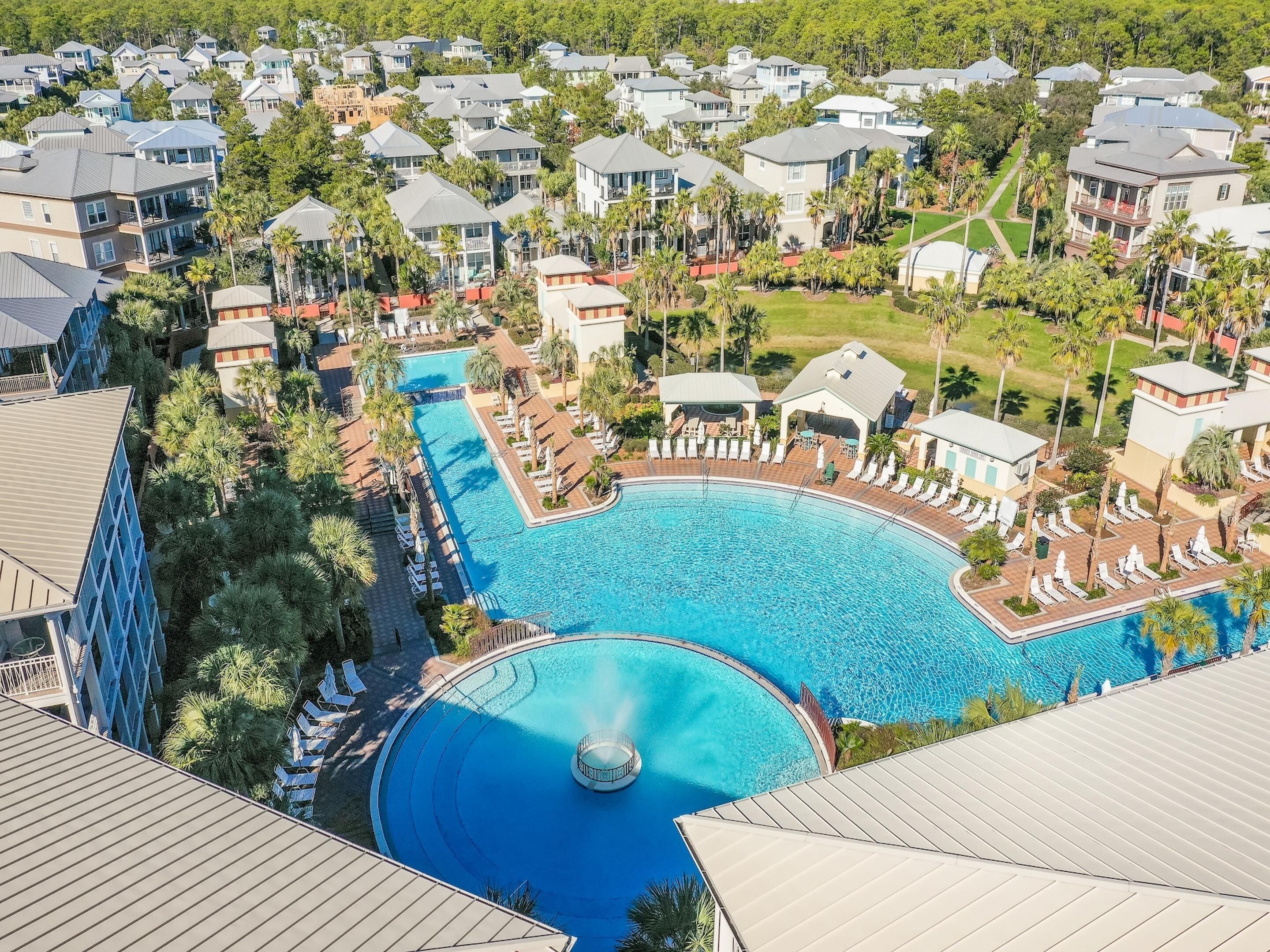 A resort with a large swimming pool, multiple lounge areas, and a variety of residential buildings.