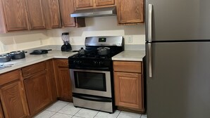 A kitchen with wooden cabinets, a stainless steel stove, a refrigerator, and a blender on the counter.