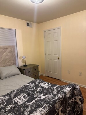 A bedroom with a bed, a dresser, a door, and a ceiling light. - NWK 457 ROOM 113-C (Newark)