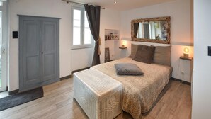 Un dormitorio con cama, lámparas de noche, un espejo, una puerta y una ventana con cortinas.