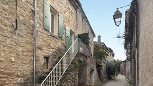 Un estrecho camino de piedra con una escalera que lleva a un edificio con contraventanas verdes.