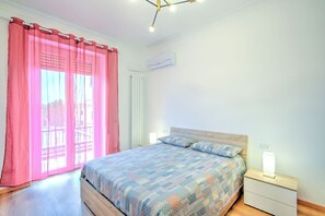 Une chambre à coucher comprenant un lit, des tables de chevet, une fenêtre avec des rideaux et un luminaire au plafond.