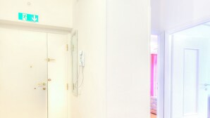 A hallway with a white door, a wall-mounted emergency exit sign, and a light switch. - Apartment in the heart of Civitavecchia (Civitavecchia)