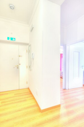 A hallway with a white door, a wall-mounted emergency exit sign, and a light switch.