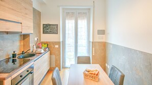 A modern kitchen with a wooden countertop, a built-in oven, and a dining area with a table and chairs. - Apartment in the heart of Civitavecchia (Civitavecchia)