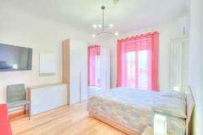 Une chambre à coucher avec un lit, une télévision, une armoire et un bureau.