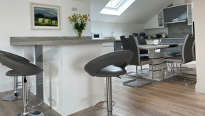 A modern kitchen with a skylight, bar stools, and a dining area. - Luxury Waterfront Apartment (Cuilmore)