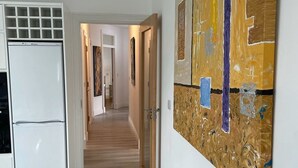 A hallway with a white refrigerator, wooden flooring, and a large abstract painting on the wall. - Luxury Waterfront Apartment (Cuilmore)