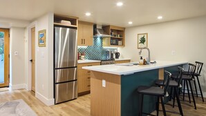 Una cucina moderna con isola centrale, elettrodomestici in acciaio inossidabile e sgabelli da bar.