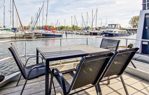 Un bote con mesa y sillas mirando hacia un puerto deportivo lleno de diferentes embarcaciones.