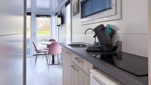 A modern kitchen with a built-in dishwasher, a sink, and a dining area with pink chairs.
