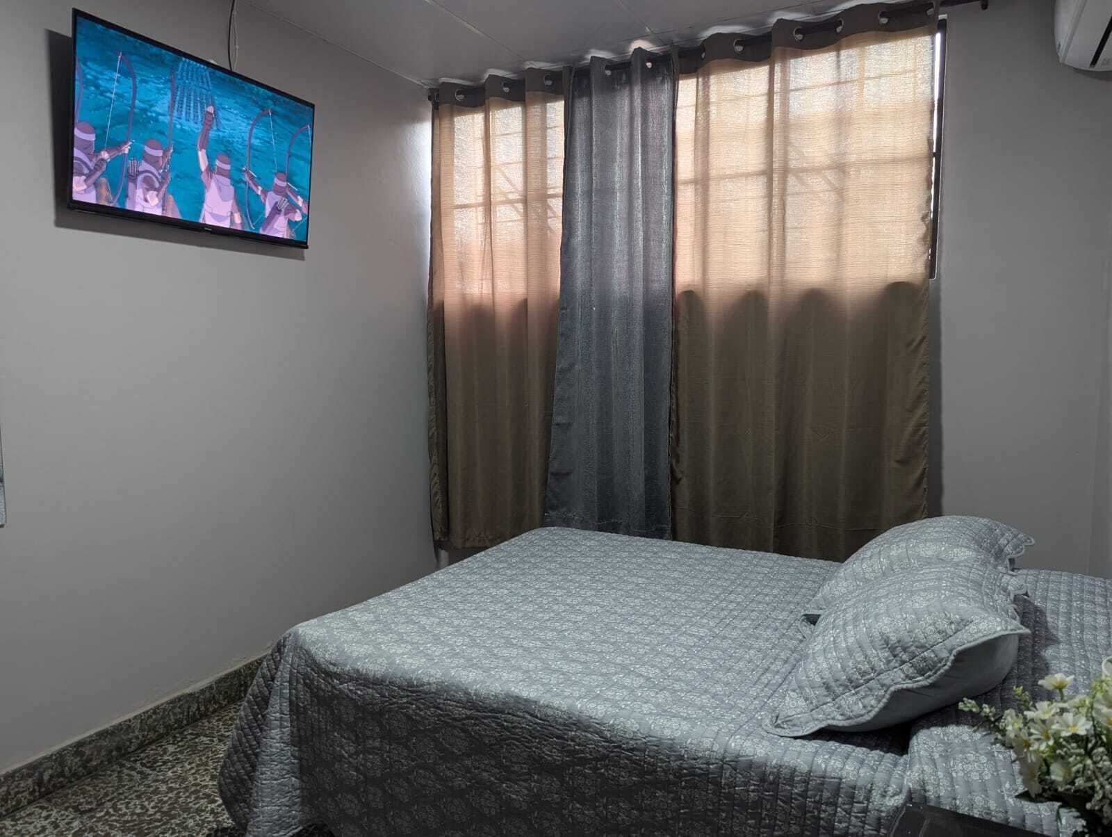 Una camera da letto con un letto, tende, una televisione e una finestra.