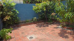 Une terrasse dallée avec un mur bleu et diverses plantes.