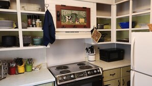 A kitchen with a stove, microwave, and various utensils.