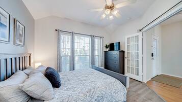 A bedroom with a bed, a dresser, a ceiling fan, and a door.