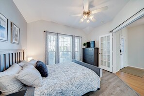 Ein Schlafzimmer mit einem Bett, einem Schminktisch, einem Deckenventilator und einer Tür.
