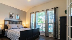 Une chambre à coucher avec un lit, des lampes de chevet, une fenêtre avec des rideaux et une porte.